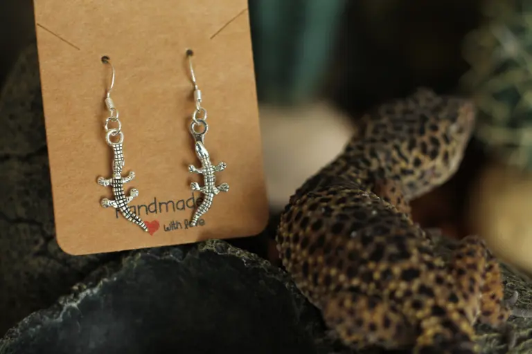 Une paire de boucle d'oreilles exposée à côté d'un gecko.